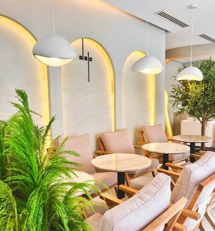 Salle claire de Don't Be Chai : arches lumineuses, fauteuils en bois et plantes
