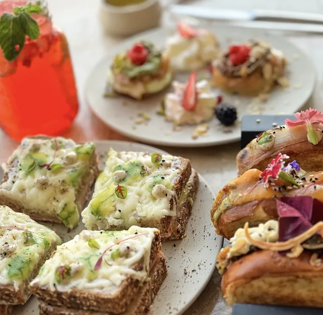 Assiette de tartines gratinées à l'avocat, plateau de mignardises et boisson rouge glacée à la menthe