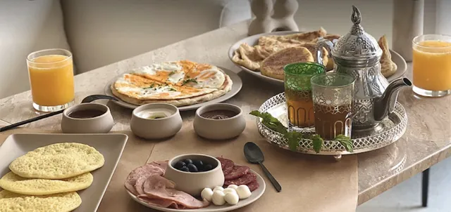 Petit-déjeuner : crêpes, galettes, charcuterie, olives et thé à la menthe dans une théière marocaine
